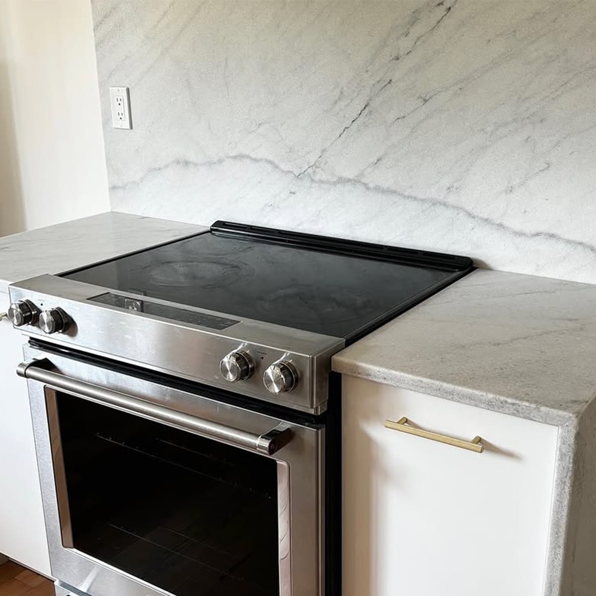 A luxurious kitchen featuring Smokey White Marble countertops and backsplash, with soft white tones, smoky gray veining, and elegant lighting.